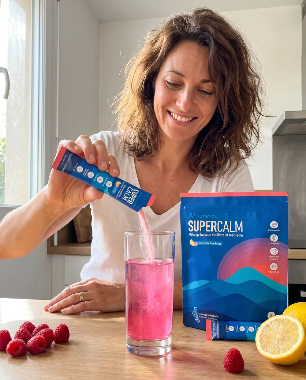 Femme souriante qui boit SuperCalm dans sa cuisine